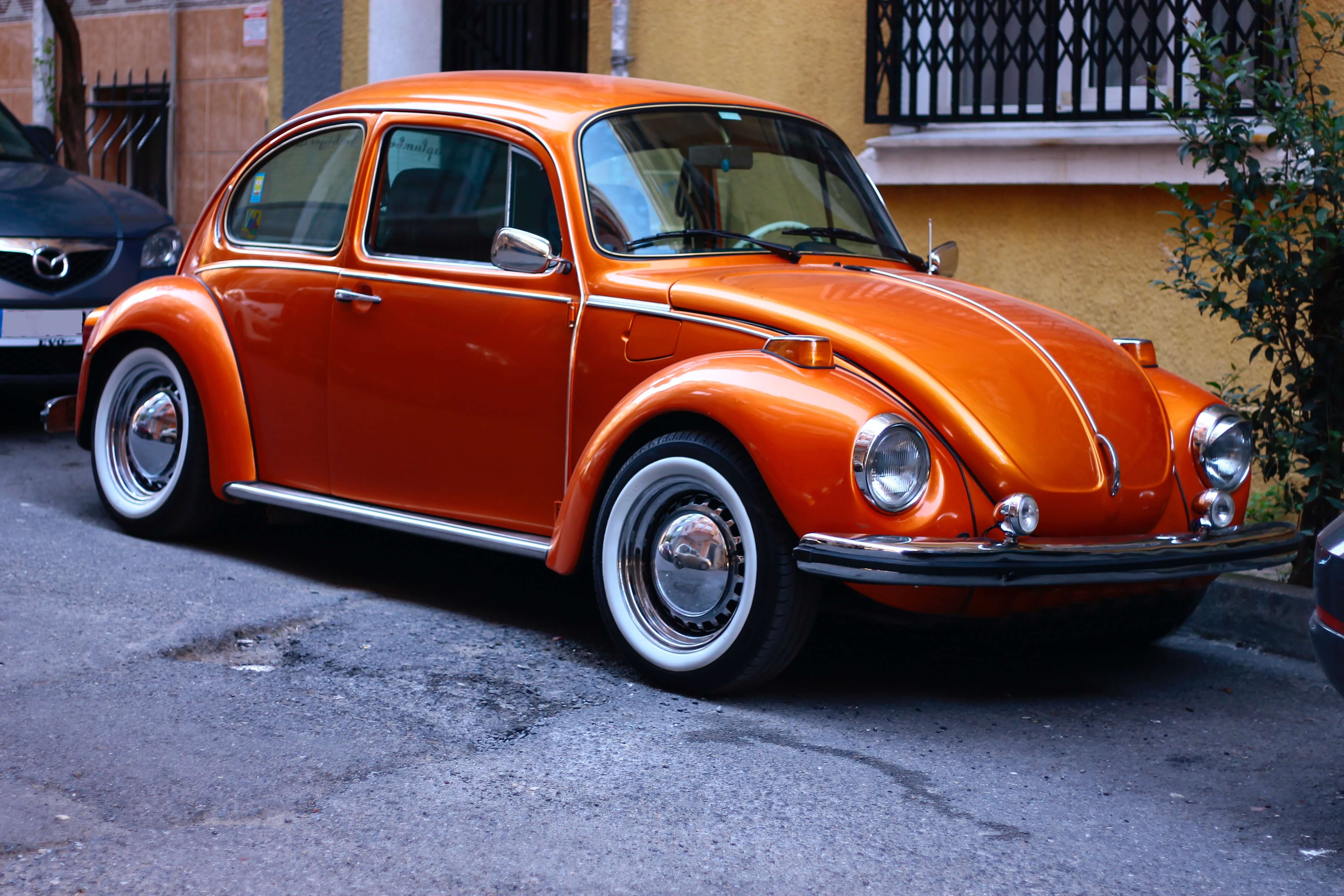 Una imagen de un Volkswagen Escarabajo naranja, que captura el color vibrante y llamativo del icónico coche compacto, evocando una sensación de diversión, estilo retro y nostalgia.